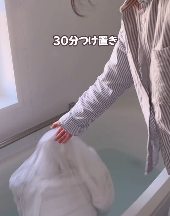 浴槽に張ったお湯にカーテンを沈める様子