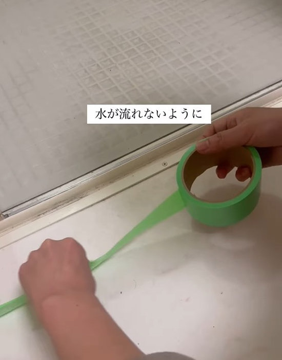 養生テープをドアレールの外側に貼る様子