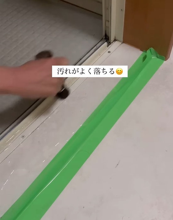 ブラシでドアレールの外側を掃除する様子