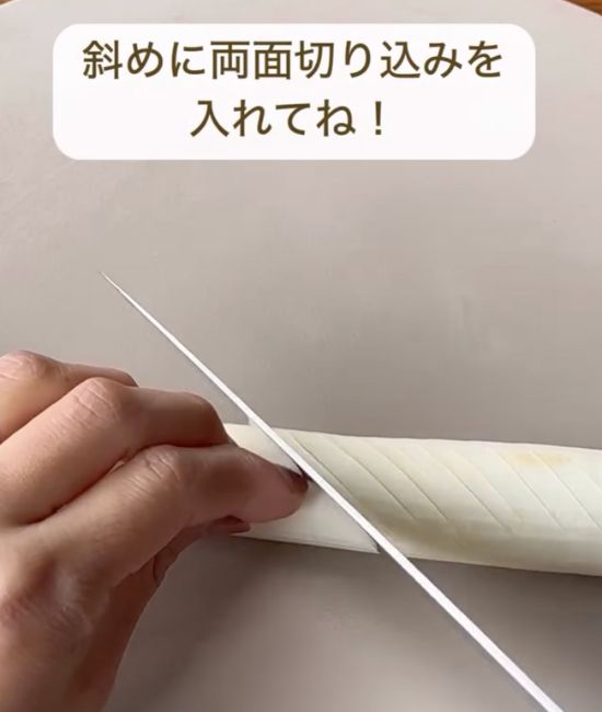 長ネギに包丁で斜めに切り込みを入れる様子