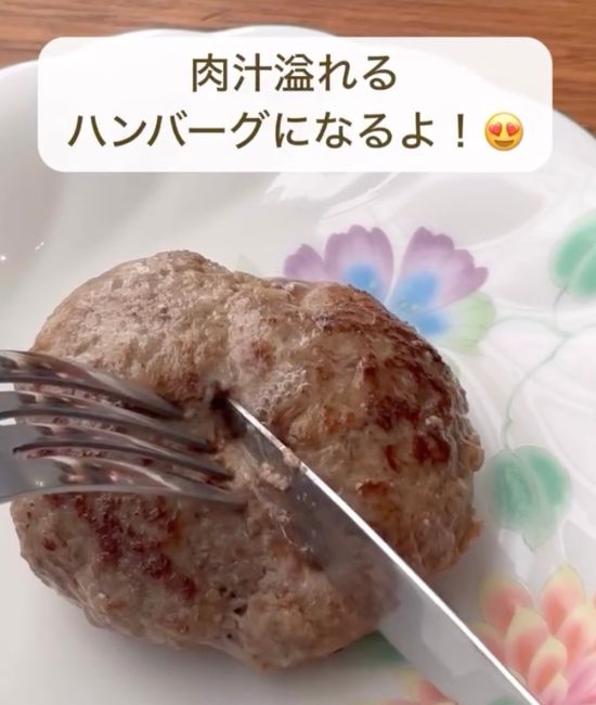 焼けたハンバーグを皿に取りナイフとフォークで切ろうとしている様子