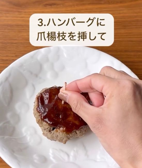ソースをかけたハンバーグの中央につまようじを刺す様子