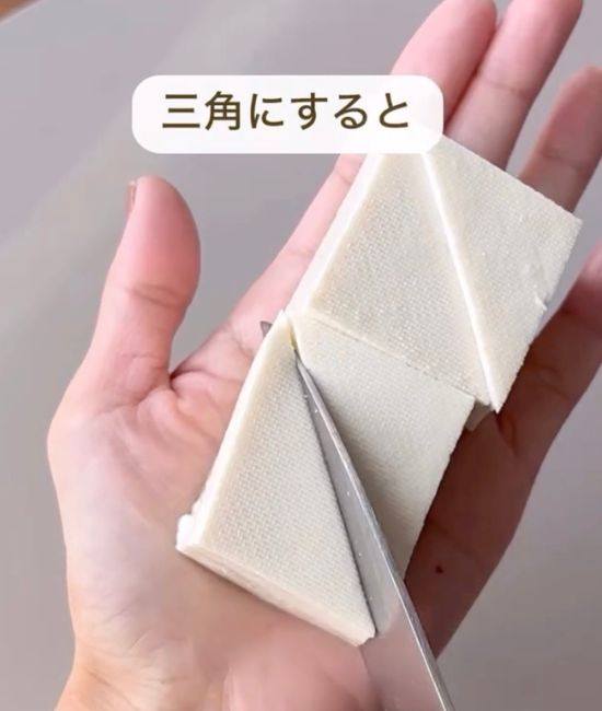 四角に切った豆腐に対角線上に包丁を入れて三角形に切る様子