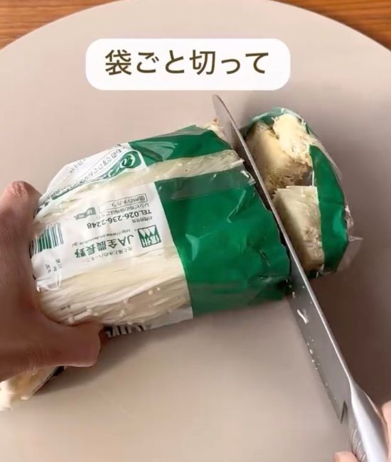 袋に入った状態でエノキの石づき部分を包丁で切る様子