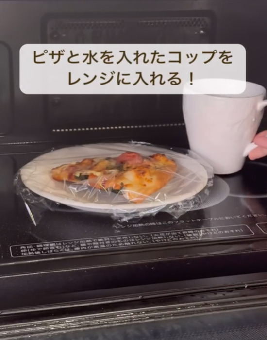 ラップをかけたピザと水の入ったコップを電子レンジに入れる様子