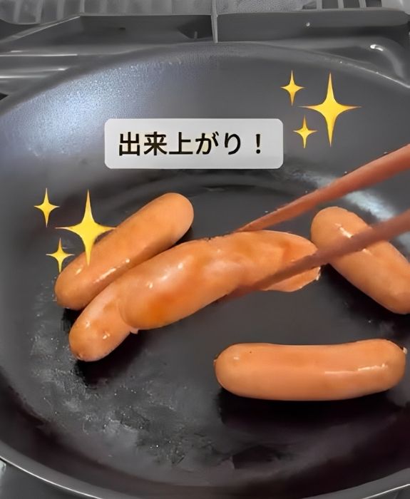焼き色が付いたウインナーを箸で持ち上げる様子