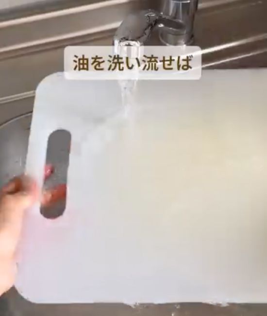 サラダ油を垂らして磨いたまな板を水道水で洗い流す様子