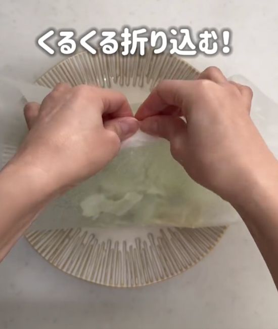 クッキングシートの口を合わせて折り込む様子