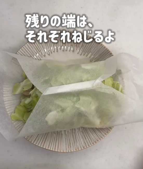 焼きそばの麺と具材をのせたクッキングシートの先端を合わせて折りたたんだ様子