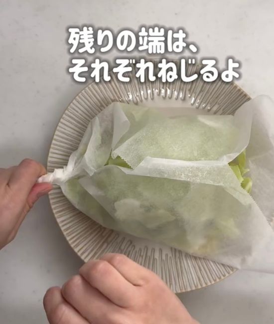 焼きそばの麺と具材をのせたクッキングシートの端をねじる様子