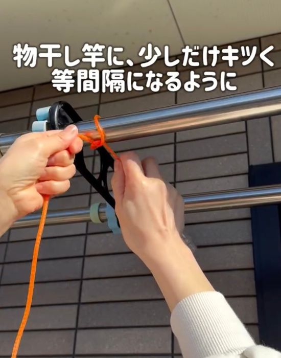 ビニール縄跳びの端を物干しざおの端にくくりつける様子