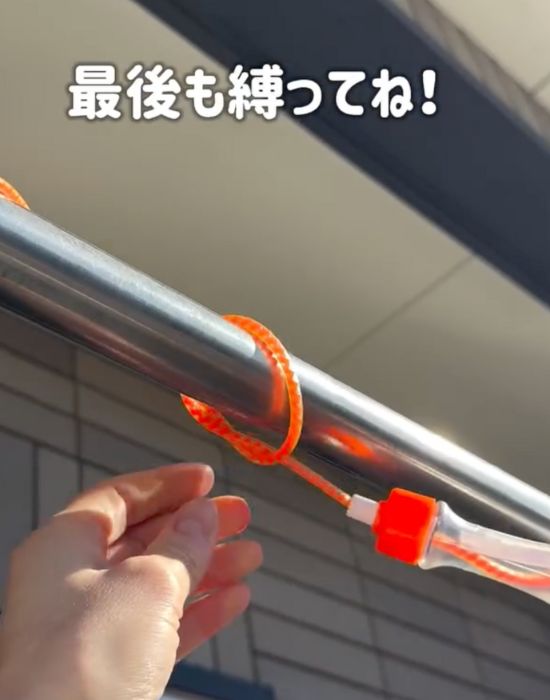 ビニール縄跳びの端を物干しざおにきつくくくりつける様子