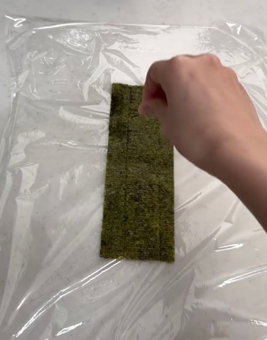 ラップの上に敷いたのりの上に塩を振る様子