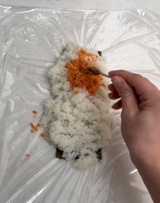 のりの上にのせたご飯の上半分に具材をのせる様子
