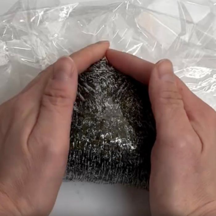 手で三角を作るようにラップの上から形を整える様子