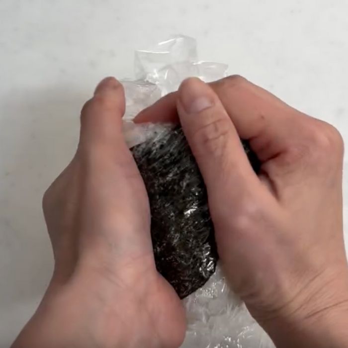 ラップの上からおにぎりの形を両手で整える様子