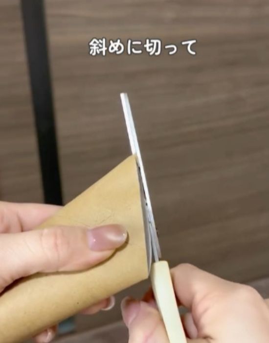 トイレットペーパーの芯をはさみで斜めに切る様子