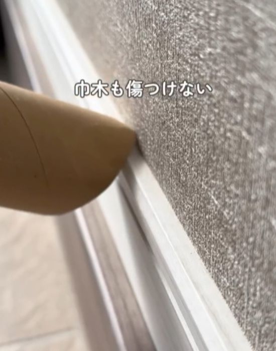 巾木のゴミをトイレットペーパーの芯を付けた掃除機で吸い取る様子