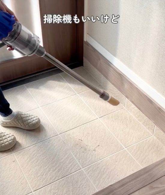玄関に集めたゴミに掃除機を向ける様子