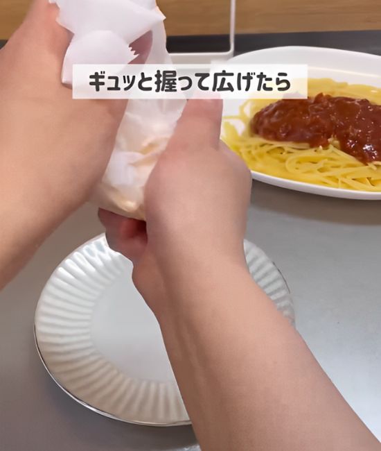 加熱したスライスチーズをのせたままクッキングシートを丸めて握る様子