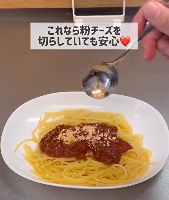 お皿に盛ったミートソーススパゲティに作った粉チーズをかける様子