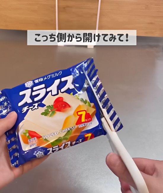 スライスチーズの袋の横側にはさみをいれて切る様子