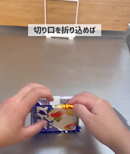 スライスチーズの袋の切り口を内側に折り込む様子