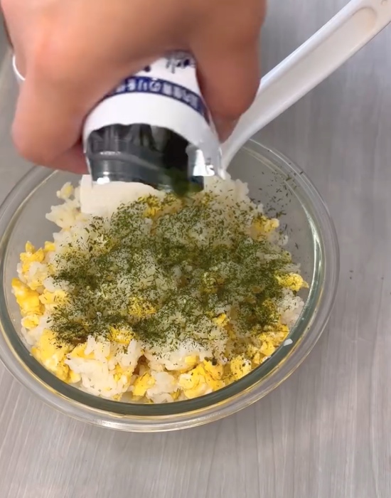 卵を混ぜた入ったご飯にバターと青のりをかける様子
