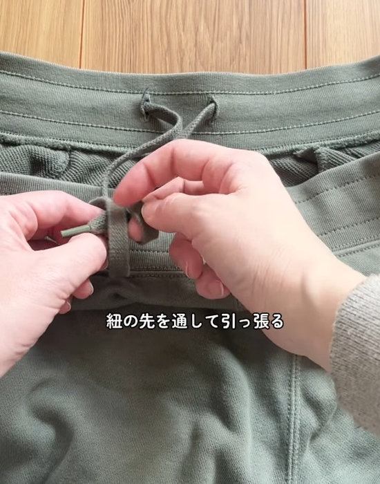 ズボンの紐の輪に紐を通す様子