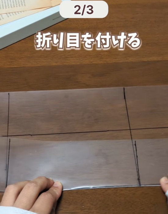 クリアファイルに書いた線に沿って折る様子