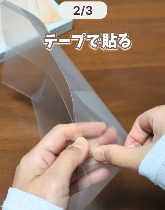 切れ込みを入れたクリアファイルを重ねてテープで留める様子