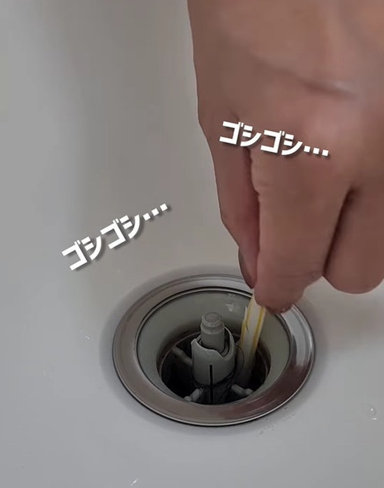 ストローの掃除棒で排水口を掃除している様子