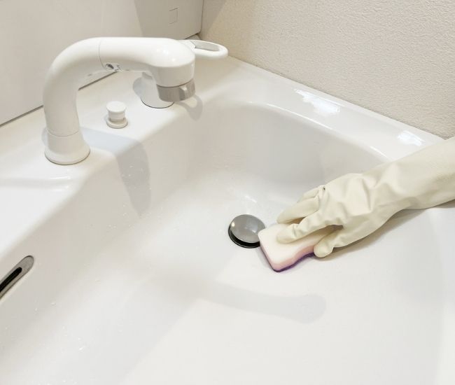 洗面台をスポンジでこすり洗いしている様子