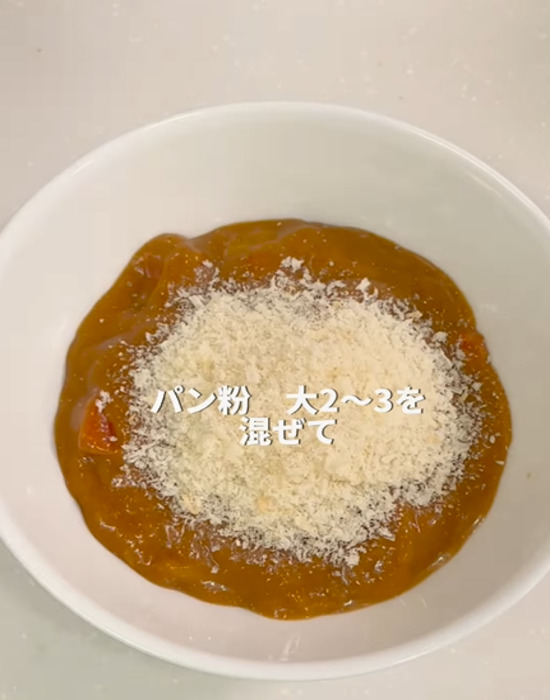 お皿に入れたレトルトカレーにパン粉を入れる様子
