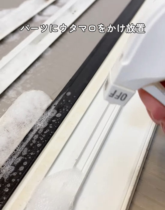 浴室のドアレールに洗剤を吹きかけている様子