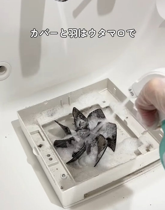 トイレの換気扇のカバーとシャッターを洗面台で洗う様子