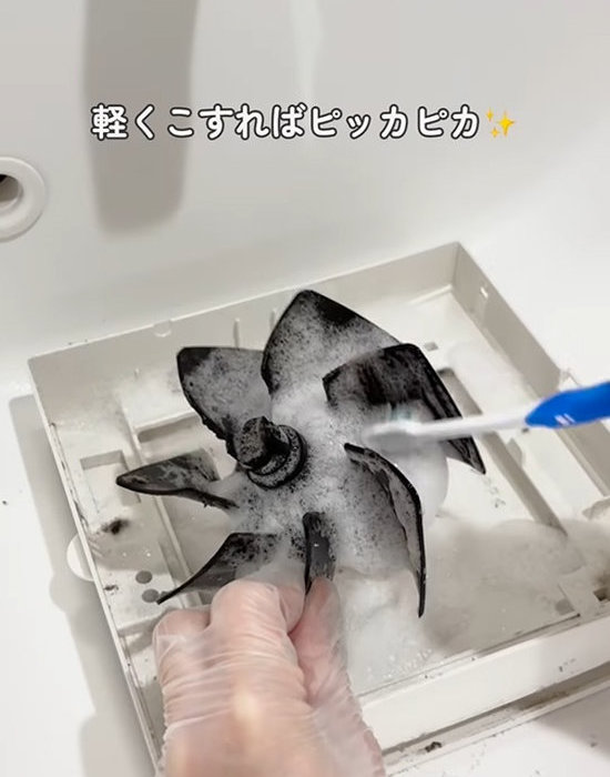 トイレの換気扇のカバーを歯ブラシで掃除する様子