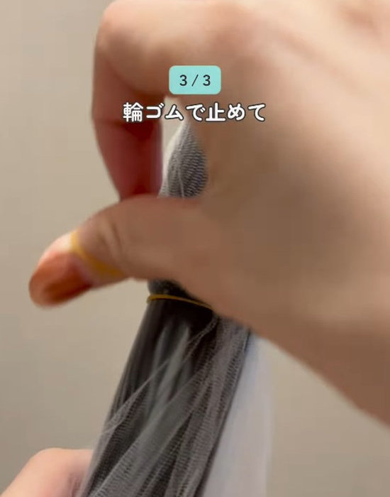 掃除機の先端にかぶせた排水口ネットを輪ゴムで留める様子