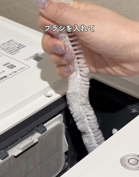 ワイヤーブラシを洗濯機の乾燥経路の中に入れる様子