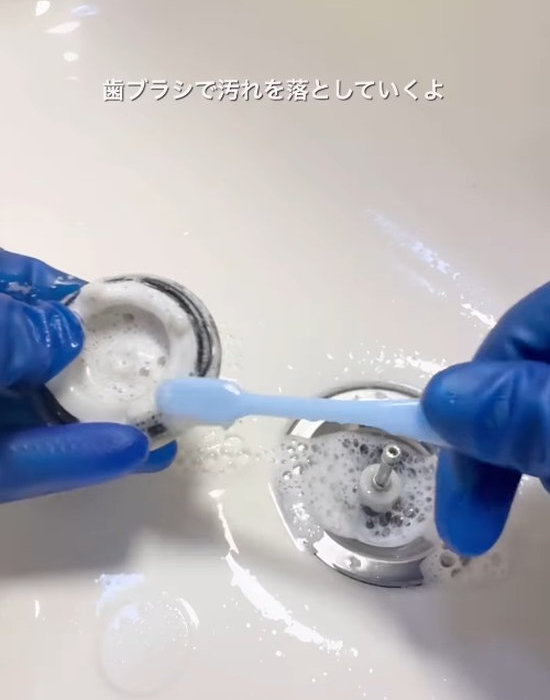 排水栓を歯ブラシで洗う様子