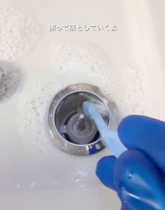 排水栓ボタンの中を歯ブラシで掃除する様子