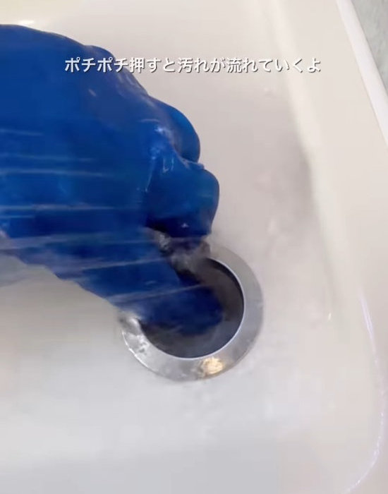 排水栓ボタンを押しながら水で洗い流す様子