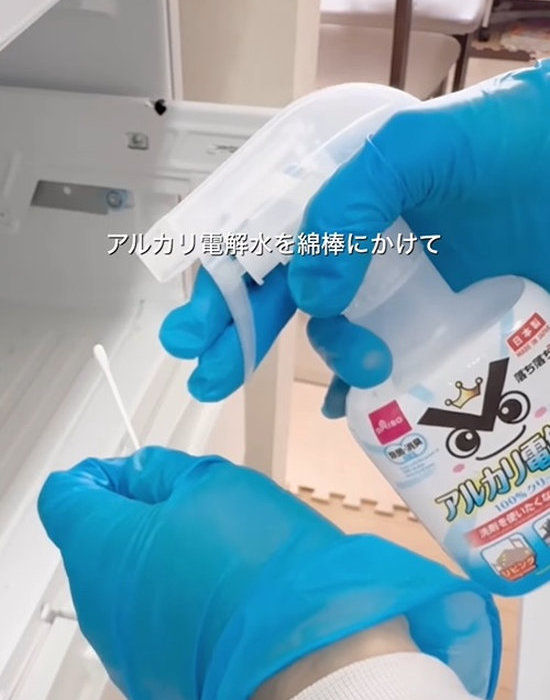 アルカリ電解水を綿棒に吹きかける様子