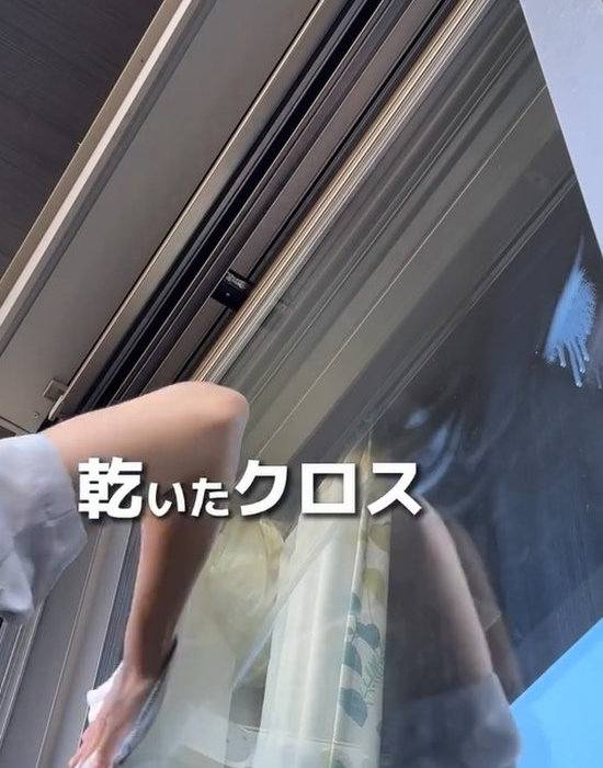 乾いたクロスで窓ガラスを拭いている様子