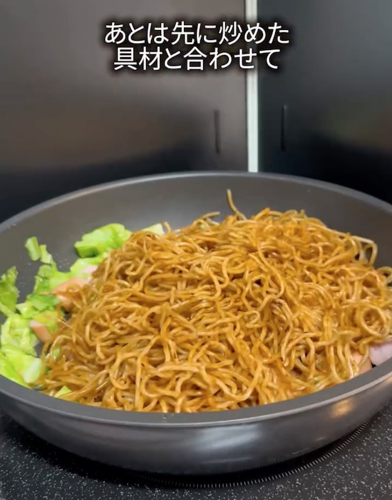 フライパンでキャベツとウインナーと麺を炒める様子