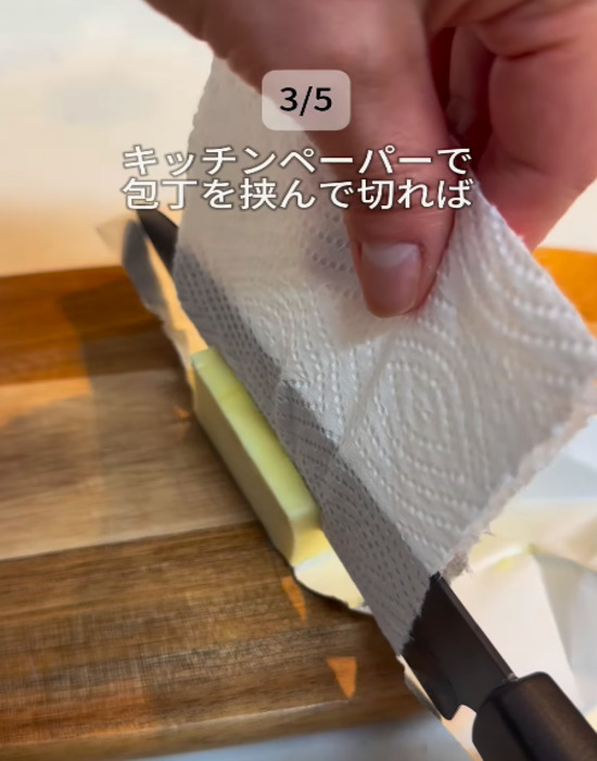 包丁をキッチンペーパーではさみバターをカットする様子