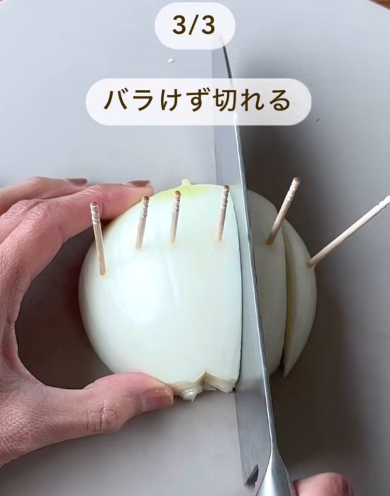 爪楊枝を刺したタマネギを包丁で切っている様子