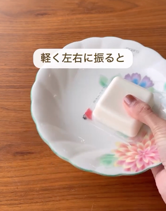 容器に入った豆腐を皿に押し付けて振る様子