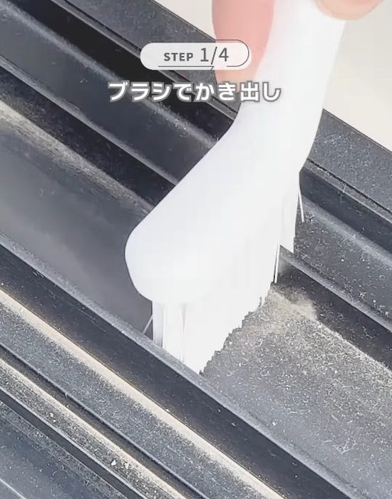 窓のサッシのゴミをブラシでかき出す様子