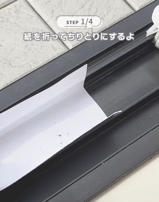 サッシにはめた紙にゴミを入れる様子